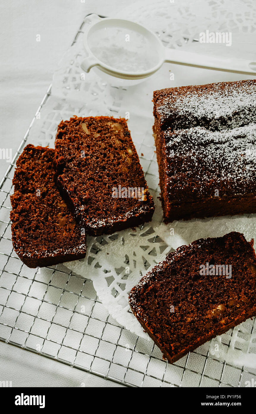 Schokoladenkuchen mit Muttern innen in Scheiben auf die Kühlung Rack  schneiden. Ein mini Sieb mit Puderzucker. Direkt oberhalb, weisser  Hintergrund Stockfotografie - Alamy
