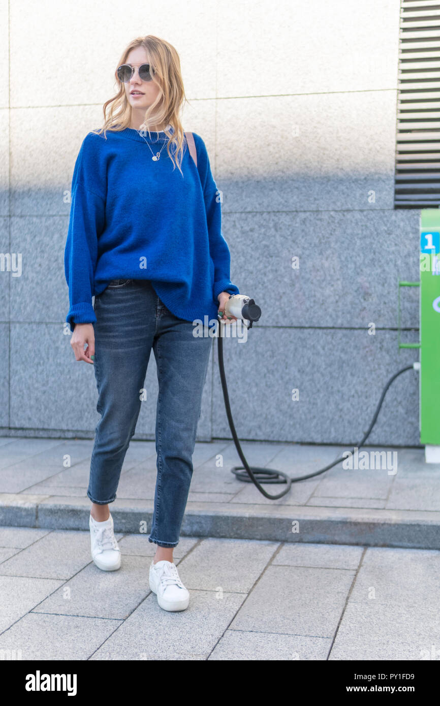 Frau am Elektroauto Ladestation Stockfoto