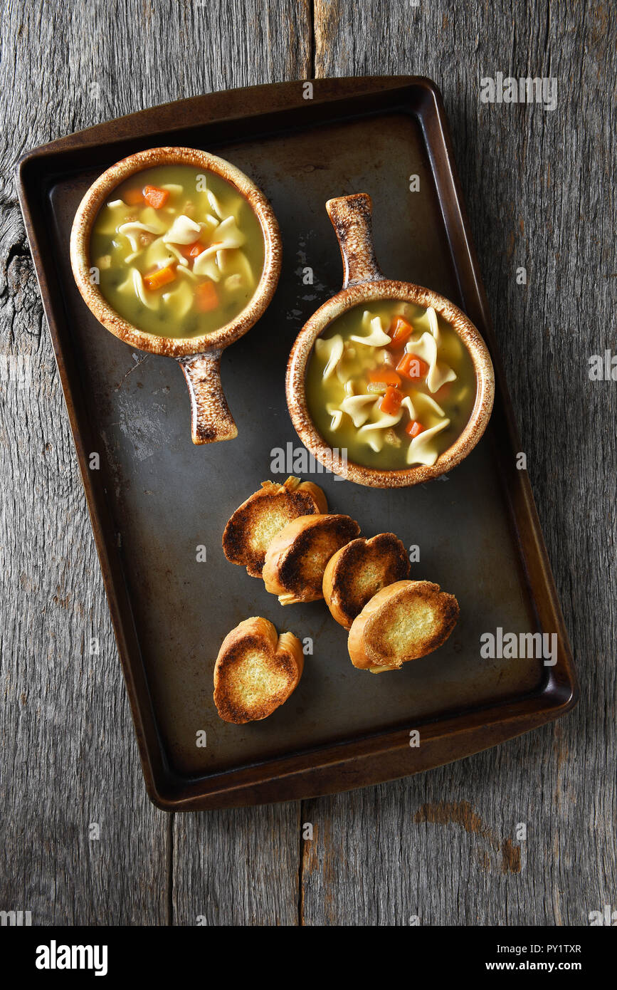 Zwei frische, hausgemachte Schüsseln mit Huhn Nudelsuppe mit Knoblauch Toast auf einem Backblech. Stockfoto