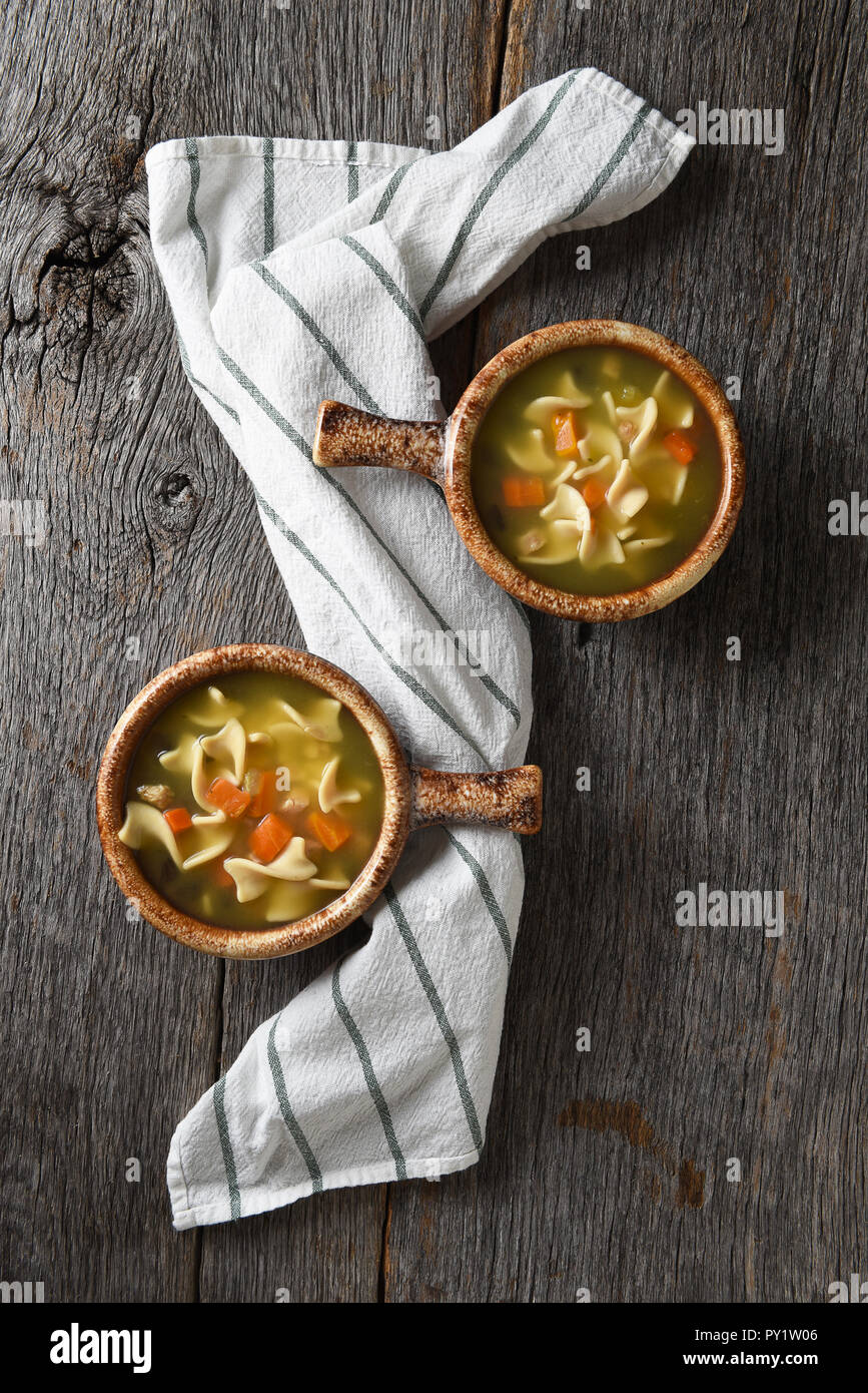 Flach mit zwei Schalen mit hausgemachten Huhn Nudelsuppe auf einem rustikalen Holztisch mit einem Küchentuch. Stockfoto