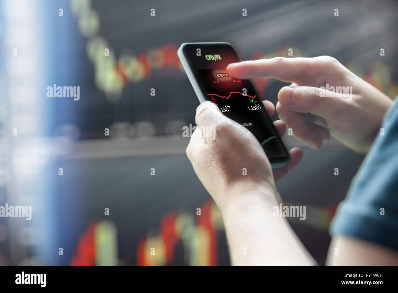 Mans hand Handy vor dunklen Börse charts Stockfoto