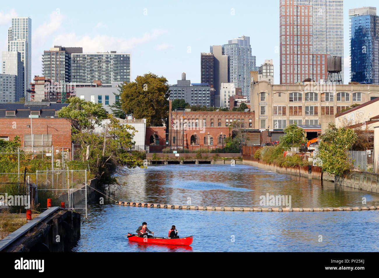 Kanufahrer auf dem Gowanus-Kanal in der Nähe der Abwasseraufbereitungsanlage der Station Gowanus mit der Skyline von Downtown Brooklyn/Fort Greene im Hintergrund Stockfoto