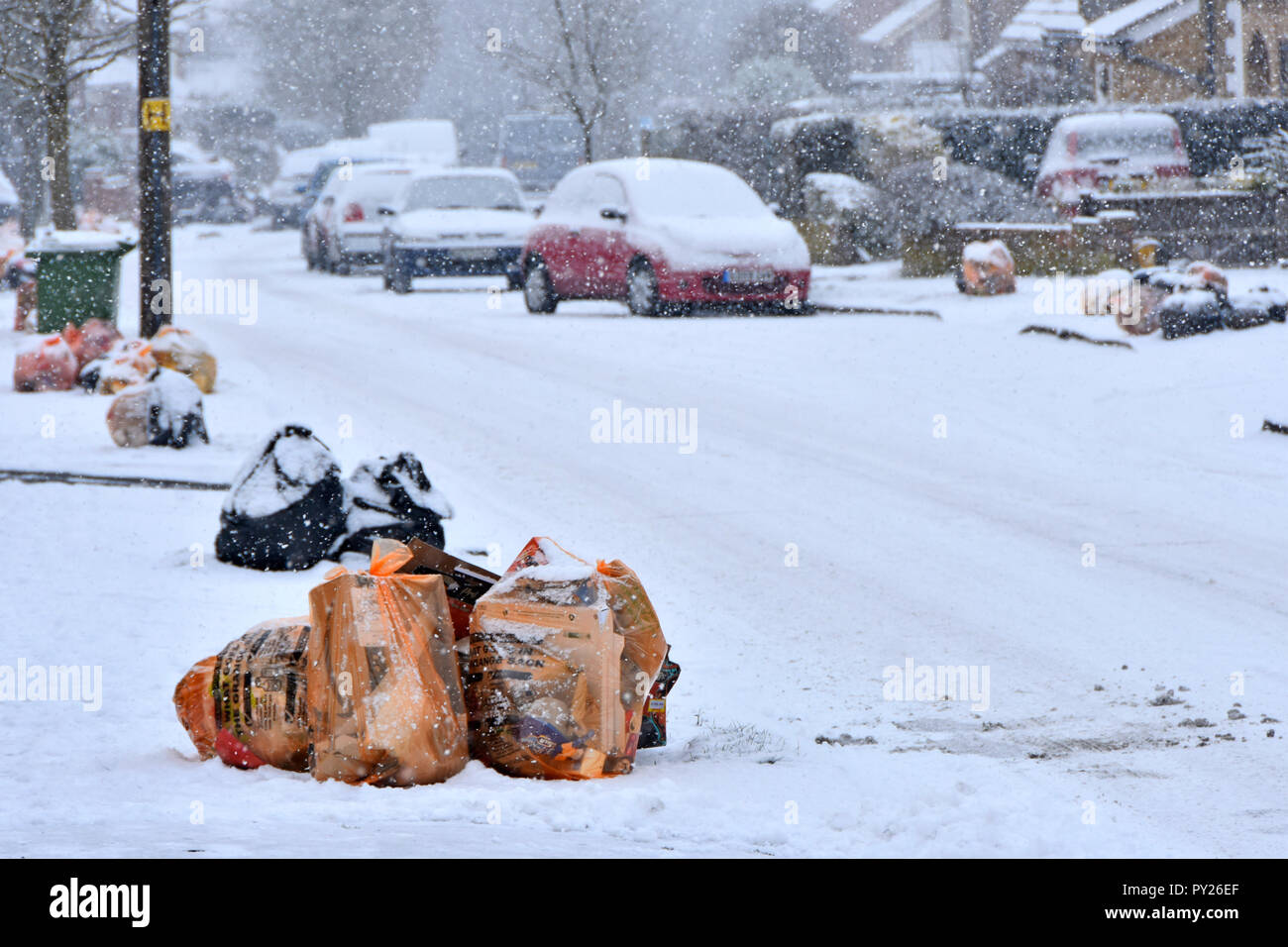Winter street scene Beutel des Recycling von Abfällen und schwarzen Sack Deponie müll Schnee auf Pflaster für die Abfallwirtschaft Team collection Lkw UK abgedeckt Stockfoto