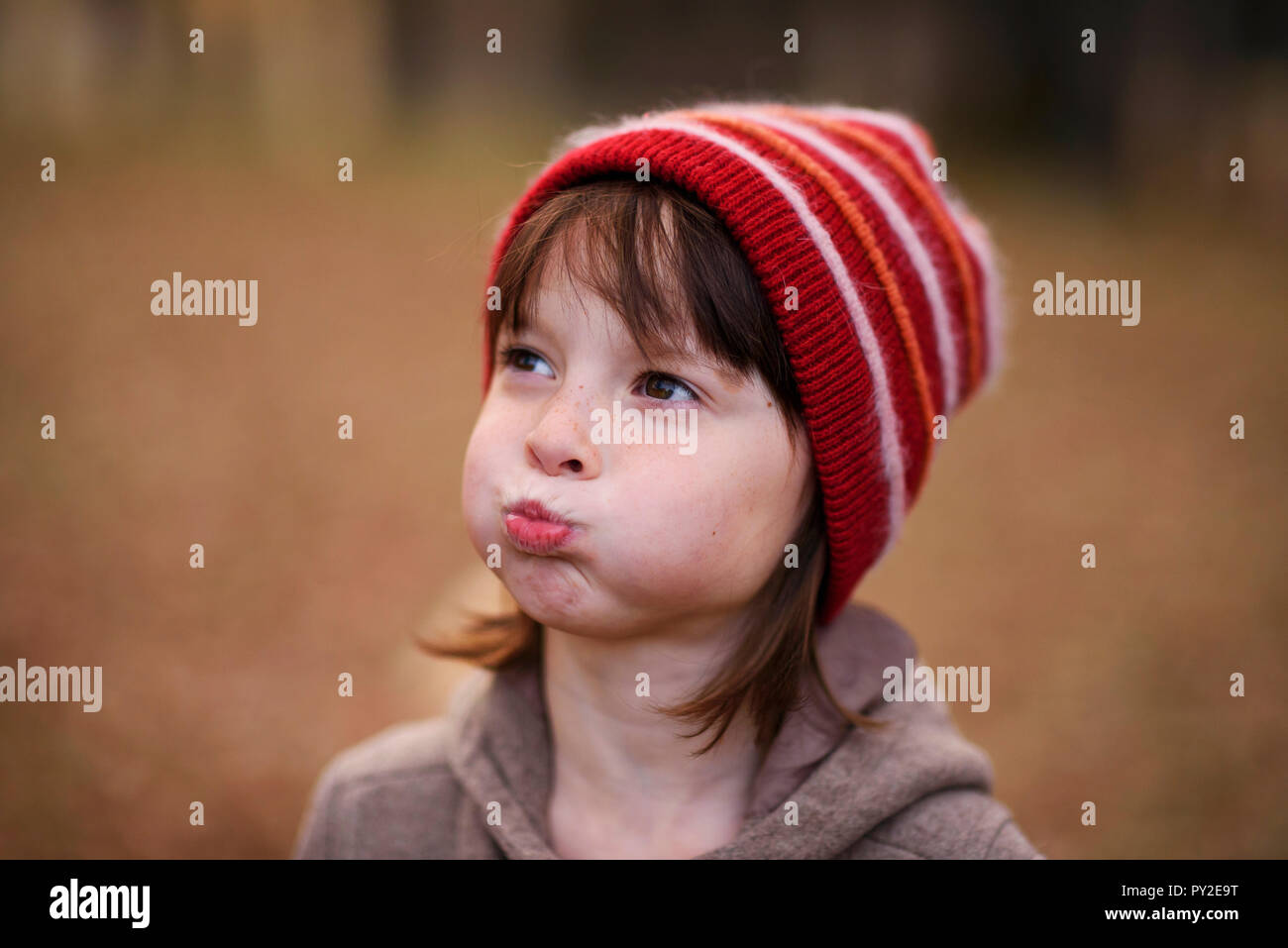 Porträt eines Mädchens in eine Wollmütze ziehen lustige Gesichter Stockfoto