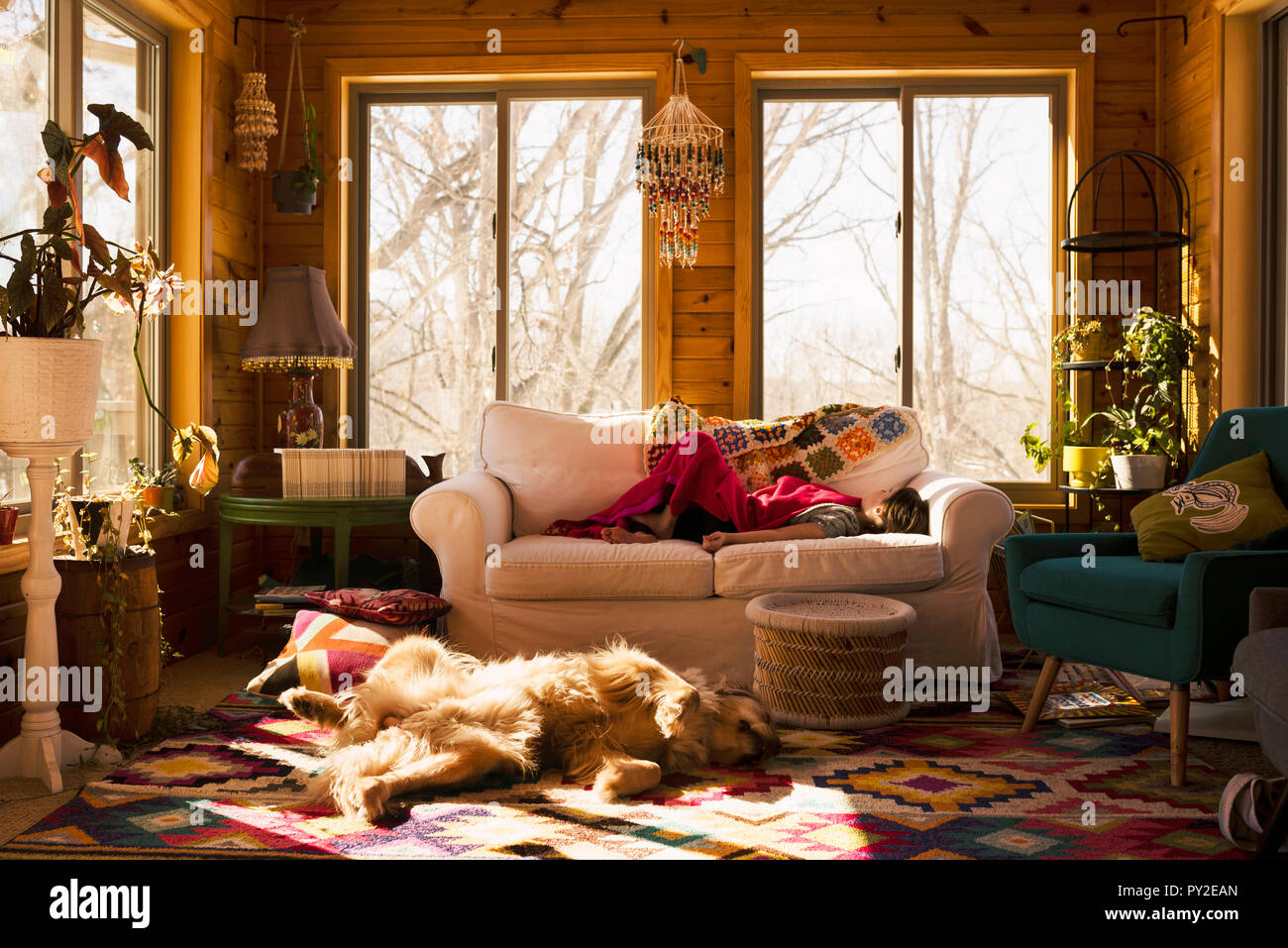 Mädchen schlafen auf einer Couch mit ihrem Hund auf dem Boden neben ihr Stockfoto