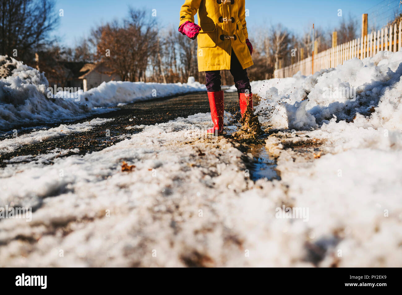 Mädchen in einer Pfütze aus schmelzendem Schnee stehend, United States Stockfoto