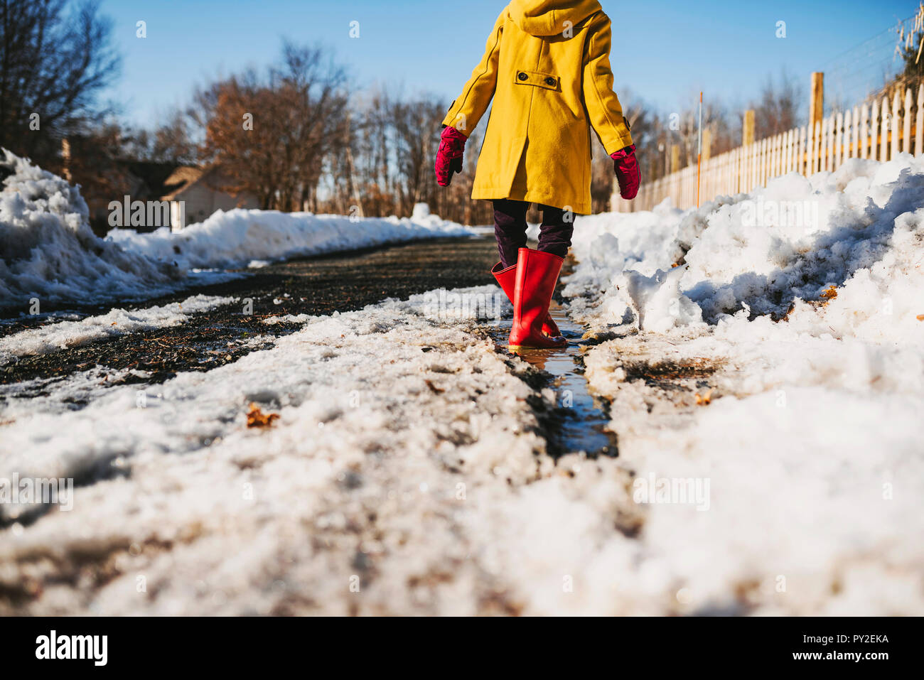 Mädchen in einer Pfütze aus schmelzendem Schnee stehend, United States Stockfoto