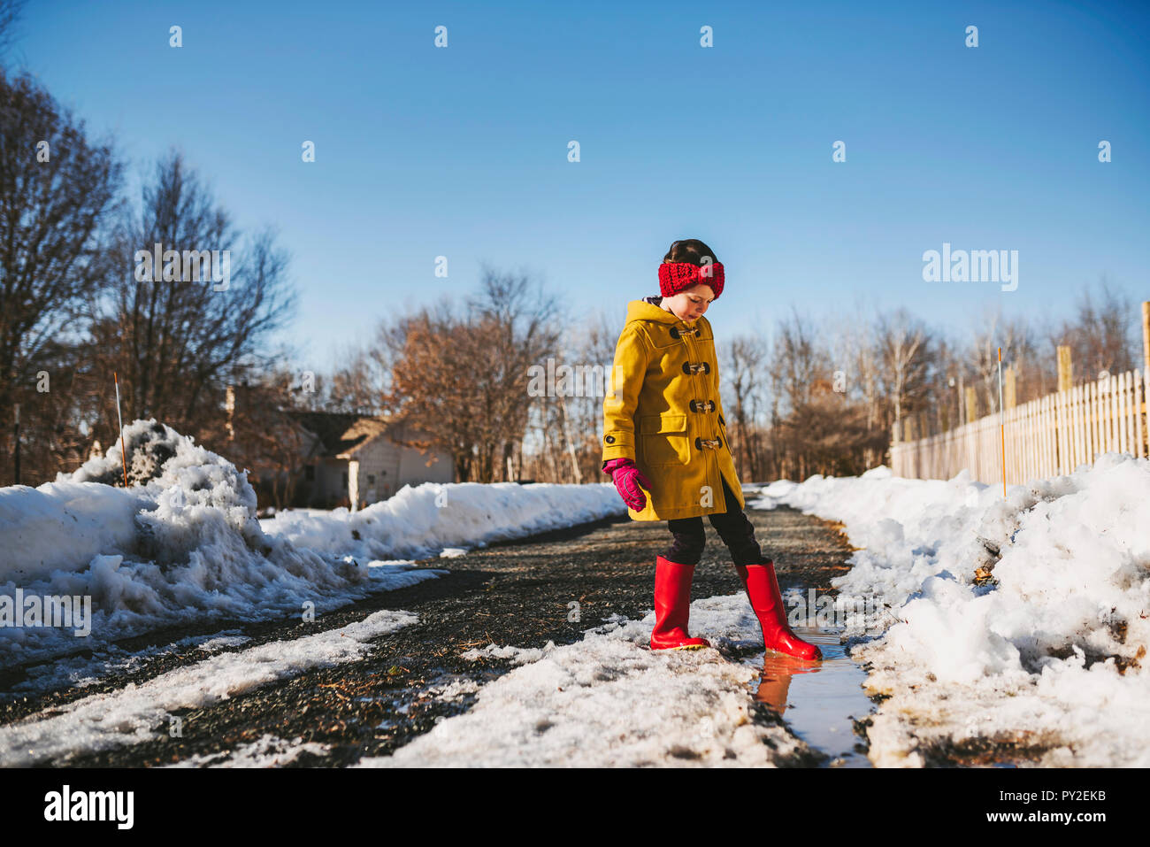 Mädchen spielen durch eine Pfütze von schmelzenden Schnee, United States Stockfoto