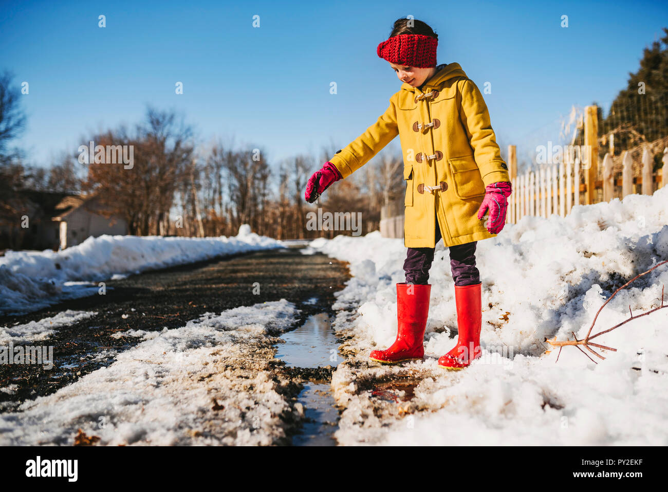 Mädchen durch eine Pfütze von schmelzenden Schnee stehend, United States Stockfoto