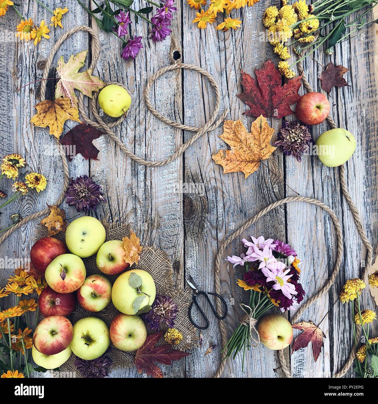Äpfel, Blätter und Herbst Blumen auf einem Holztisch Stockfoto