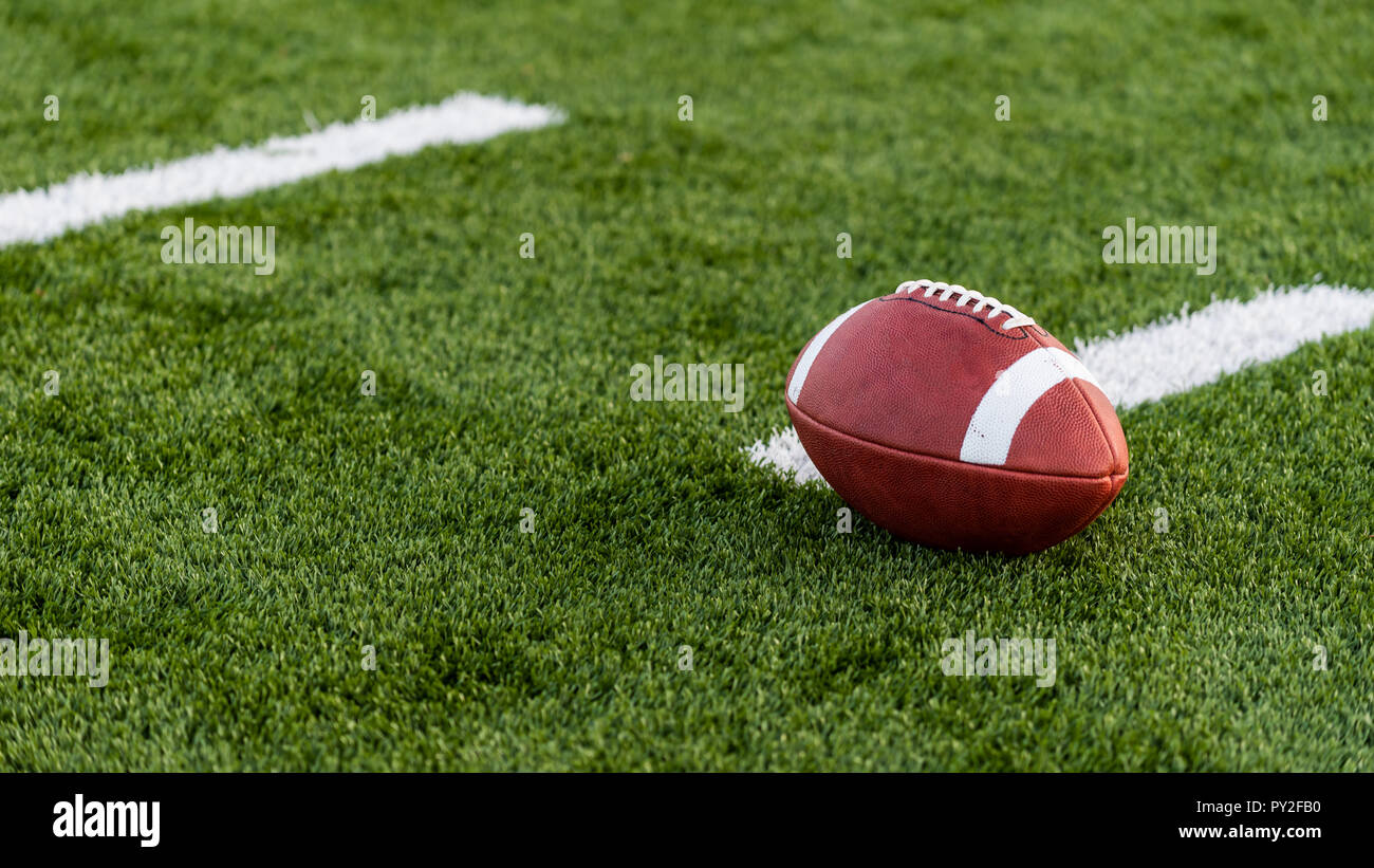 Ein braunes Leder American Football auf einem grünen Kunstrasenplatz Stockfoto