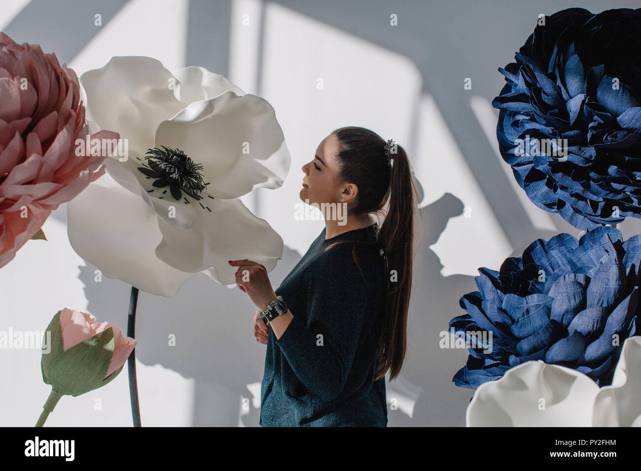 Porträt einer Frau steht neben riesigen Künstliche Blumen Stockfoto