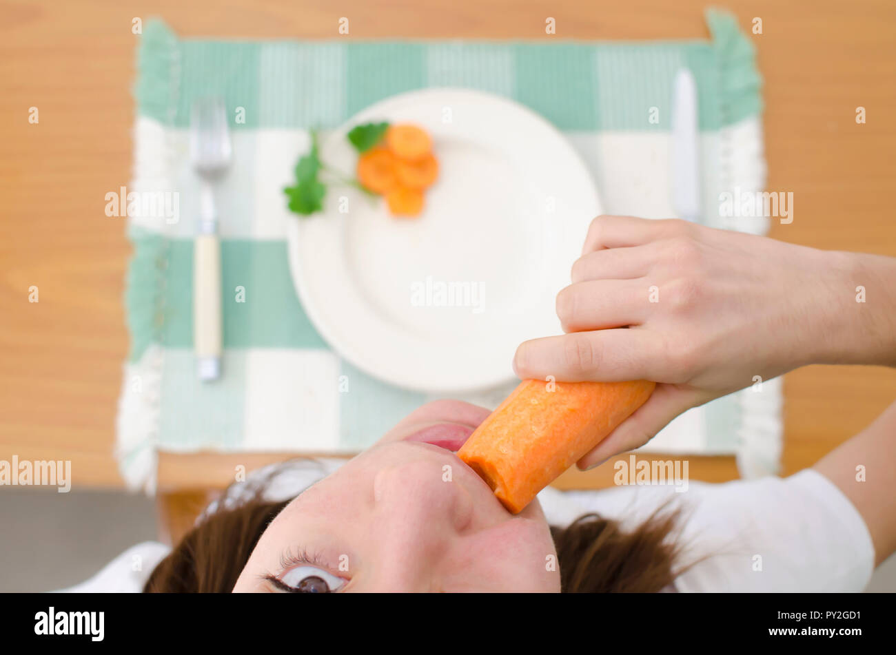 Ansicht von oben von einem Mädchen, das an einem Tisch sitzen essen eine Karotte Stockfoto