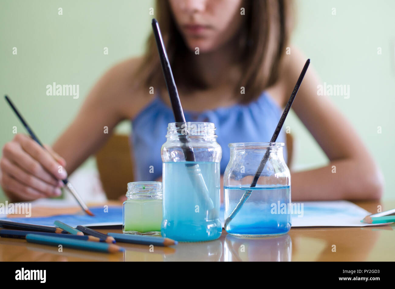 Mädchen sitzt an einem Tisch Malerei mit Aquarellen Stockfoto