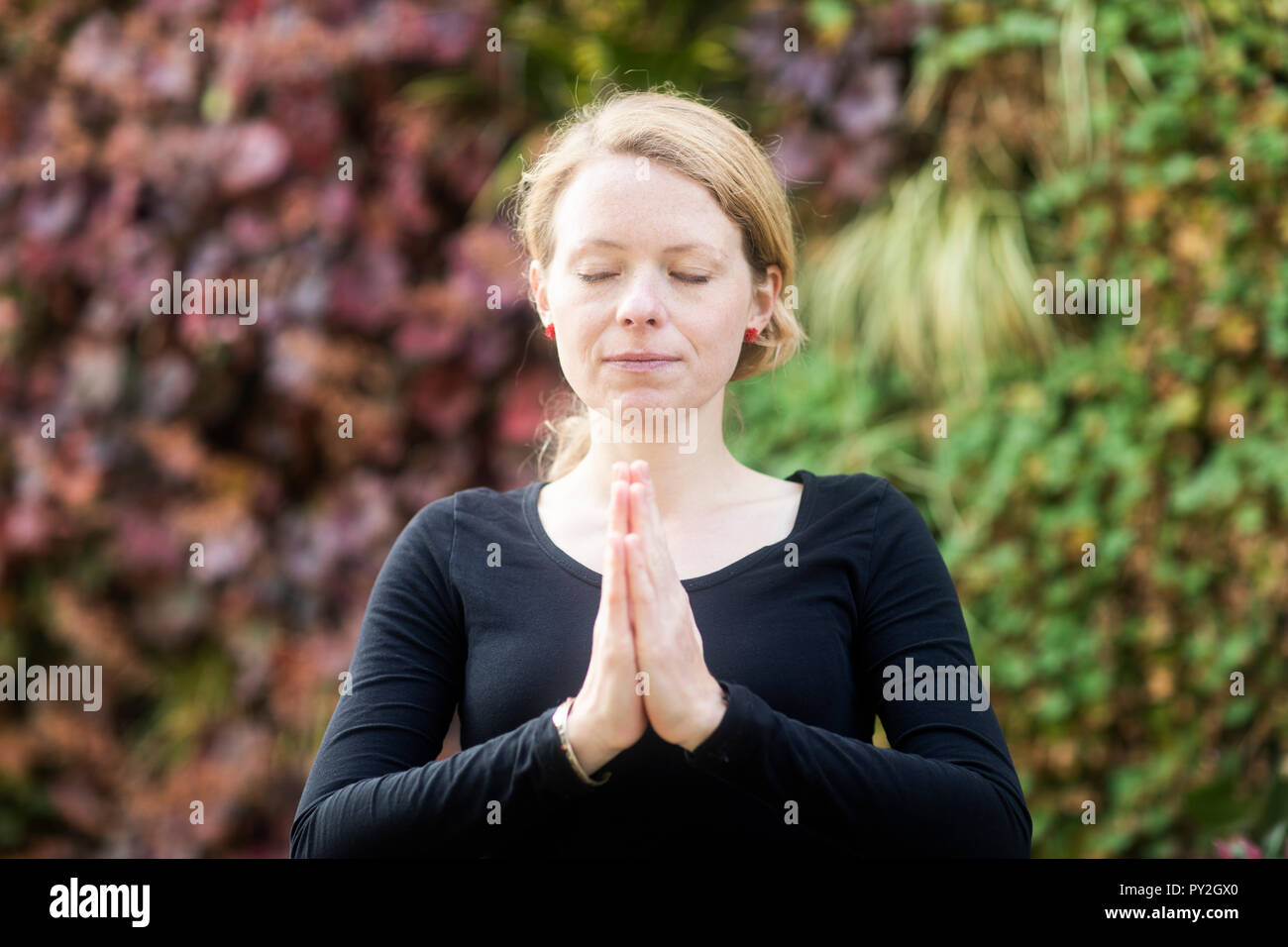 Porträt einer Frau, im Park mit ihren Hände im Gebet Position Stockfoto