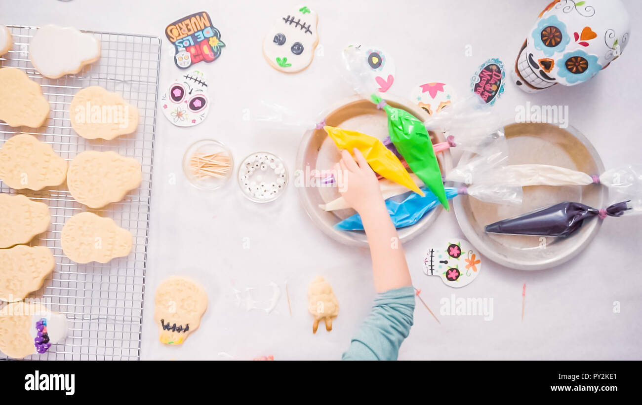 Schritt für Schritt. Flach. Kleines Mädchen dekorieren Sugar Skull cookies mit Royal icing für Dia de los Muertos Urlaub. Stockfoto