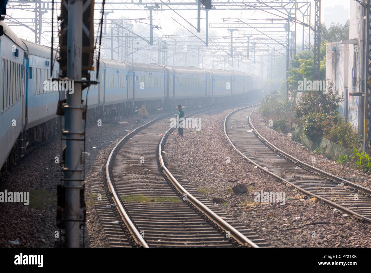 Indische Zug nähert sich Delhi Bahnhof am frühen Morgen Haze Stockfoto