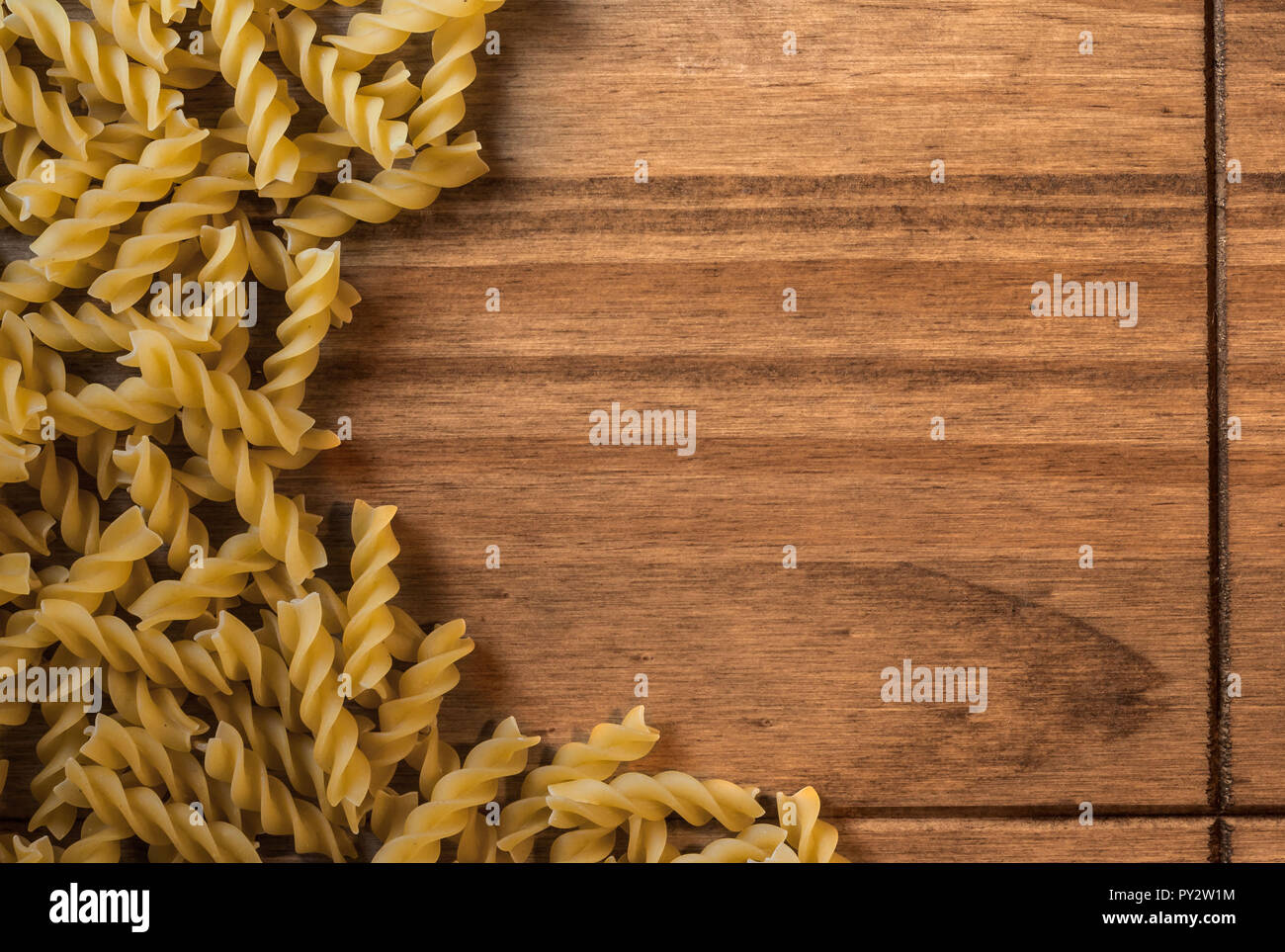 Rahmen der rohen Fusilli auf einer hölzernen Oberfläche mit Platz für Text. Essen Hintergrund für Konzepte wie italienische Speisen, Pasta Rezepte, Kohlenhydrate... Stockfoto