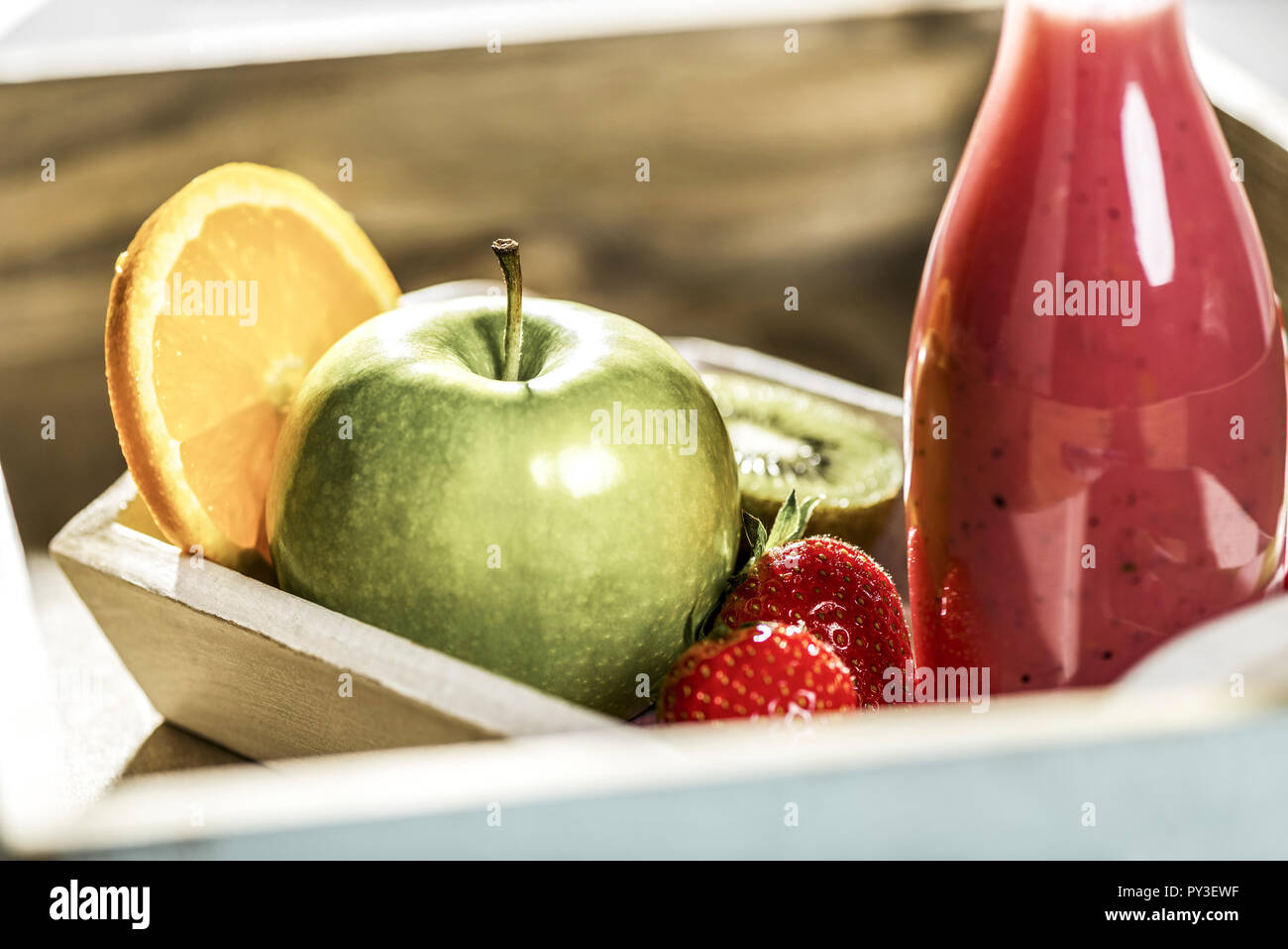 Fruchtsmoothie in Glasflasche Und Obst in Holzschale Stockfoto