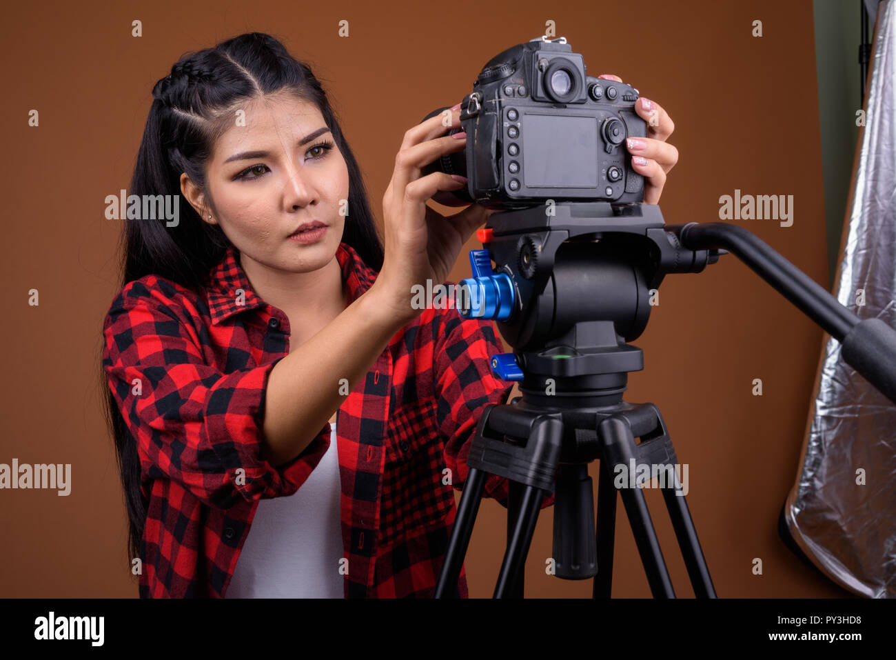 Junge asiatische Frau Fotograf Einstellen der Kamera auf Stativ Stockfoto