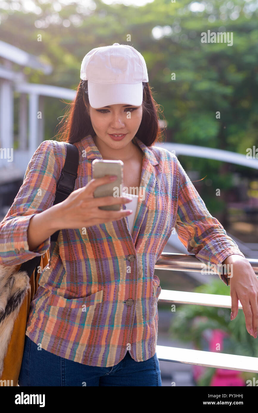 Junge schöne asiatische Frau mit Handy im Freien Stockfoto