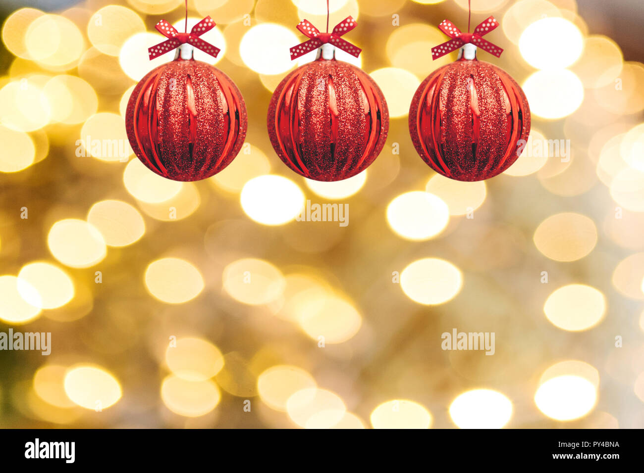 Festliche rote Kugeln oder Weihnachtsschmuck hängen in einer Reihe auf einem hellen Weihnachten Goldener Hintergrund Stockfoto