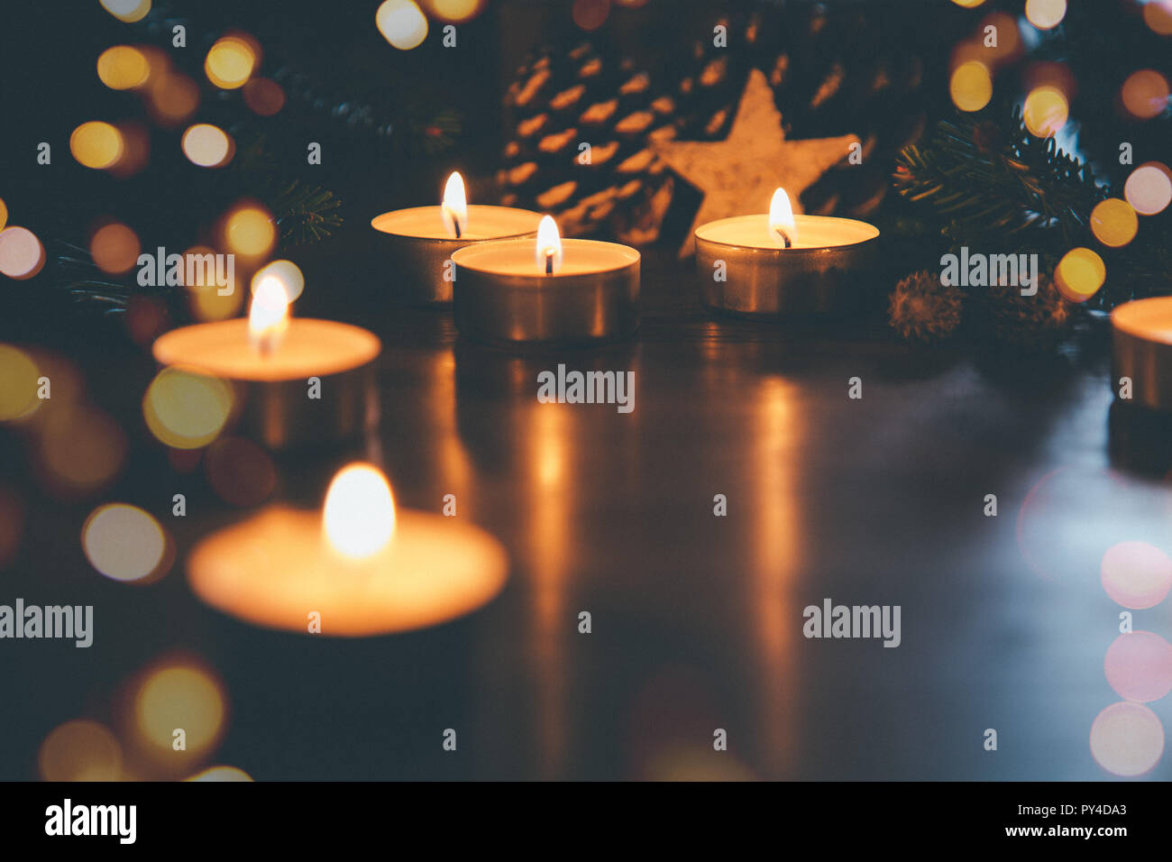 Brennen Weihnachten Kerzen auf dem Tisch mit Tannenzapfen, tannenzweigen, Dekoration und Beleuchtung. Filmkorn Effekt hinzugefügt Stockfoto