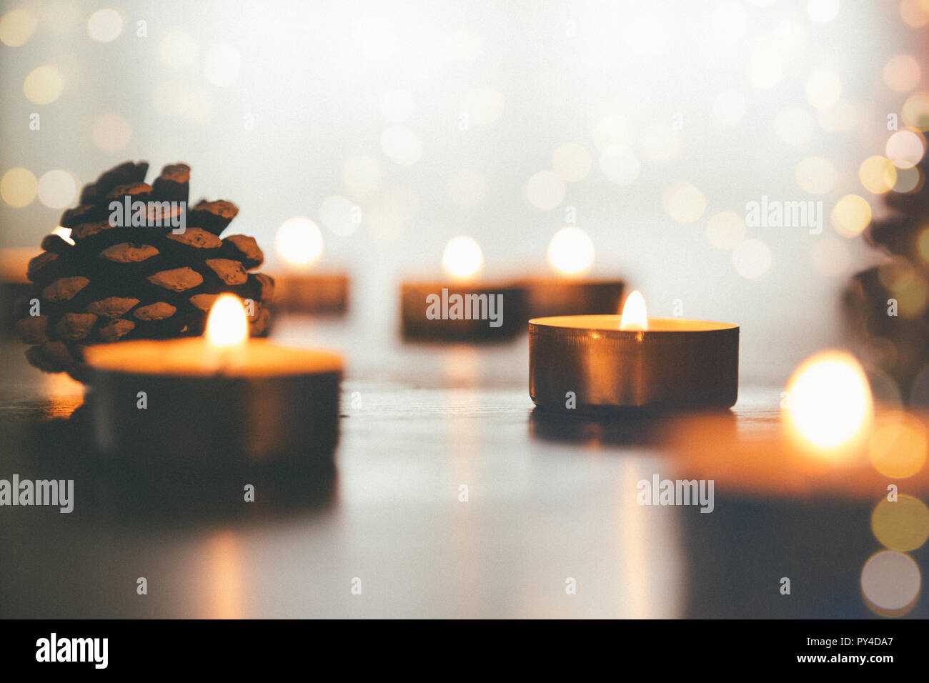 Brennen Weihnachten Kerzen auf dem Tisch mit Tannenzapfen und Lichter. Filmkorn Effekt hinzugefügt Stockfoto