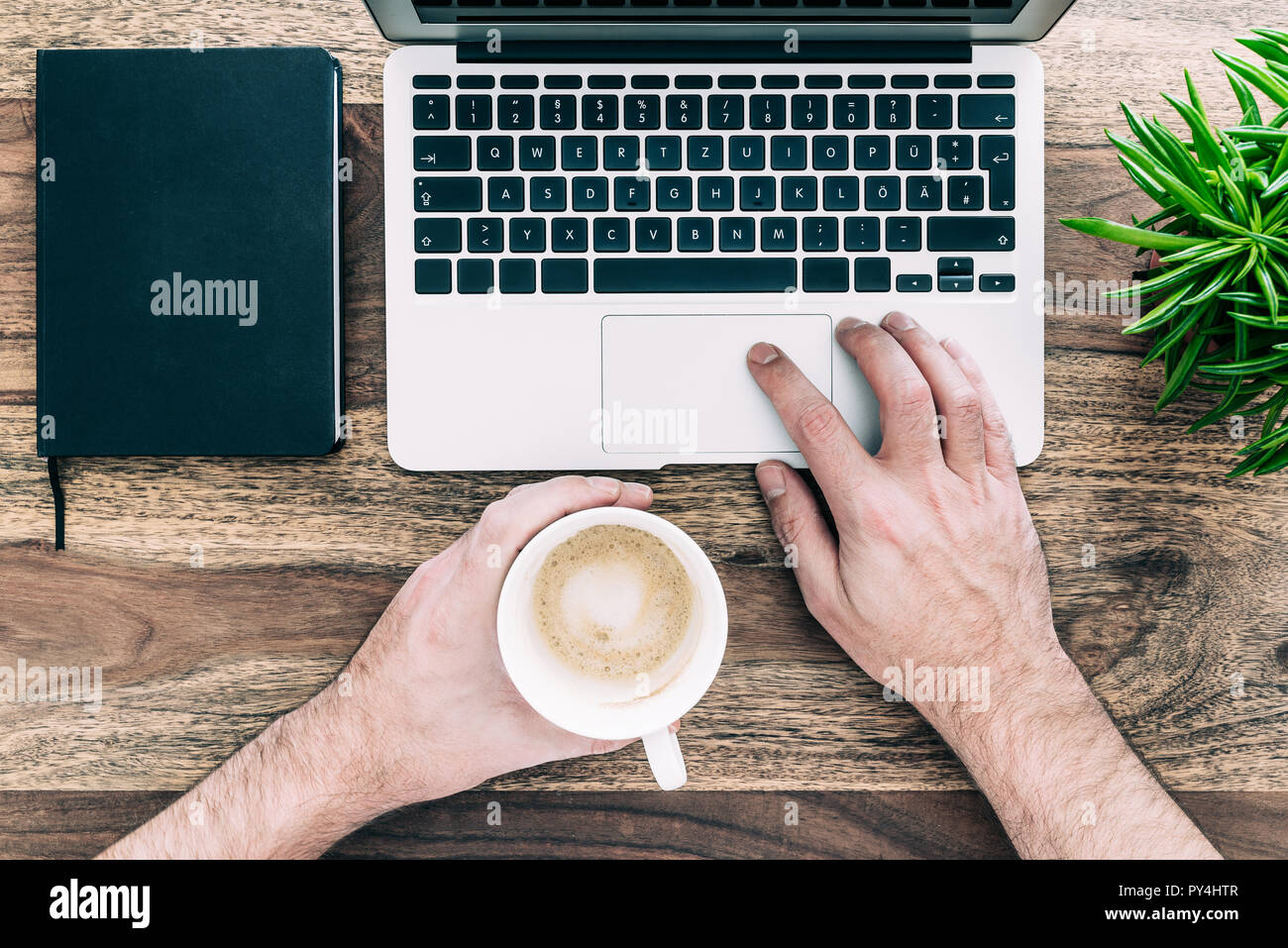 Mann mit Tasse Kaffee während der Arbeit am Laptop. Stockfoto