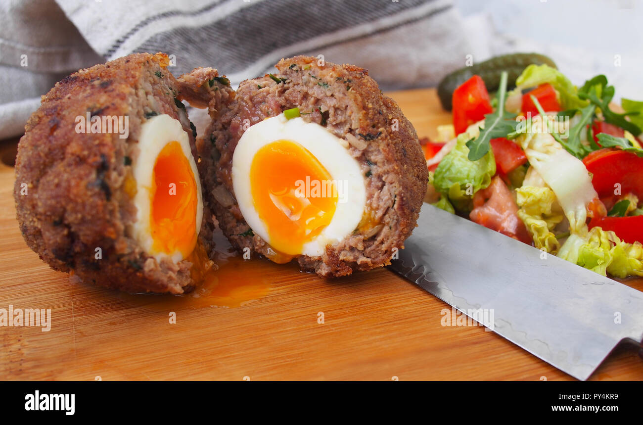 Der traditionelle cotch Ei" auf einer Holzplatte. Scotch Eiern und Salat Stockfoto