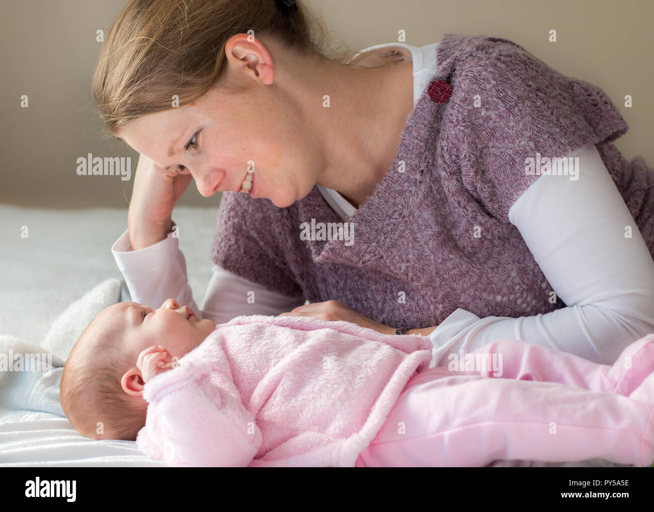 Die Mutter ihr Baby girl zur Festlegung auf dem Bett, die Interaktion von Angesicht zu Angesicht. Stockfoto