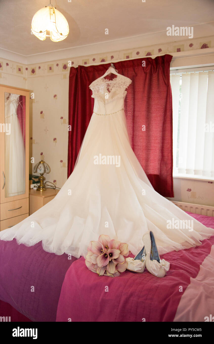 Bräute Hochzeit Kleid hängt mit Blumen und Schuhe warten auf die Bräute Hochzeit getragen zu werden. Stockfoto