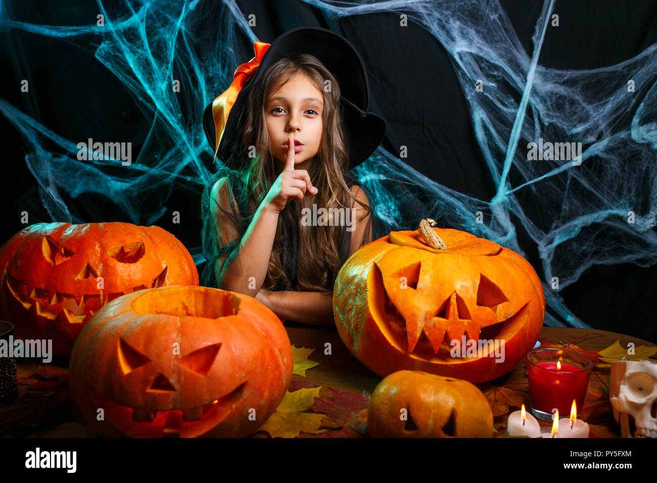 Halloween Konzept - kleines Mädchen in Hexen Kostüm Halloween feiern Stille  Geste tun posiert mit gebogenen Kürbisse über Fledermäuse und Spinnennetz  auf W Stockfotografie - Alamy