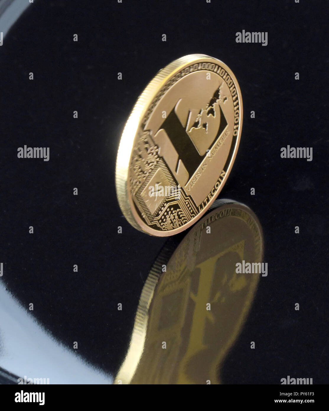 30. August 2018, Berlin: eine Litecoin Münze mit dem Aufdruck "Vires in Numeris' (Stärke in Zahlen) ist verzerrt und in einem schwarzen Oberfläche reflektiert. Das Internet Währung ist ein mathematisch gesichert, dezentrale Netzwerk und wird über blockchains Zahlungen an fast jede Person weltweit in Echtzeit zu senden soll es möglich zu machen. Mit schnellen Transaktionszeiten Litecoin ist ein zu Bitcoin ergänzen. Foto: Soeren Stache/dpa-Zentralbild/ZB Stockfoto