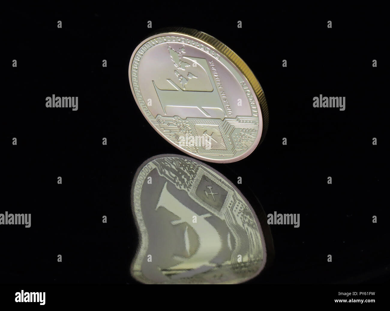 30. August 2018, Berlin: eine Litecoin Münze mit dem Aufdruck "Vires in Numeris' (Stärke in Zahlen) ist verzerrt und in einem schwarzen Oberfläche reflektiert. Das Internet Währung ist ein mathematisch gesichert, dezentrale Netzwerk und wird über blockchains Zahlungen an fast jede Person weltweit in Echtzeit zu senden soll es möglich zu machen. Mit schnellen Transaktionszeiten Litecoin ist ein zu Bitcoin ergänzen. Foto: Soeren Stache/dpa-Zentralbild/ZB Stockfoto