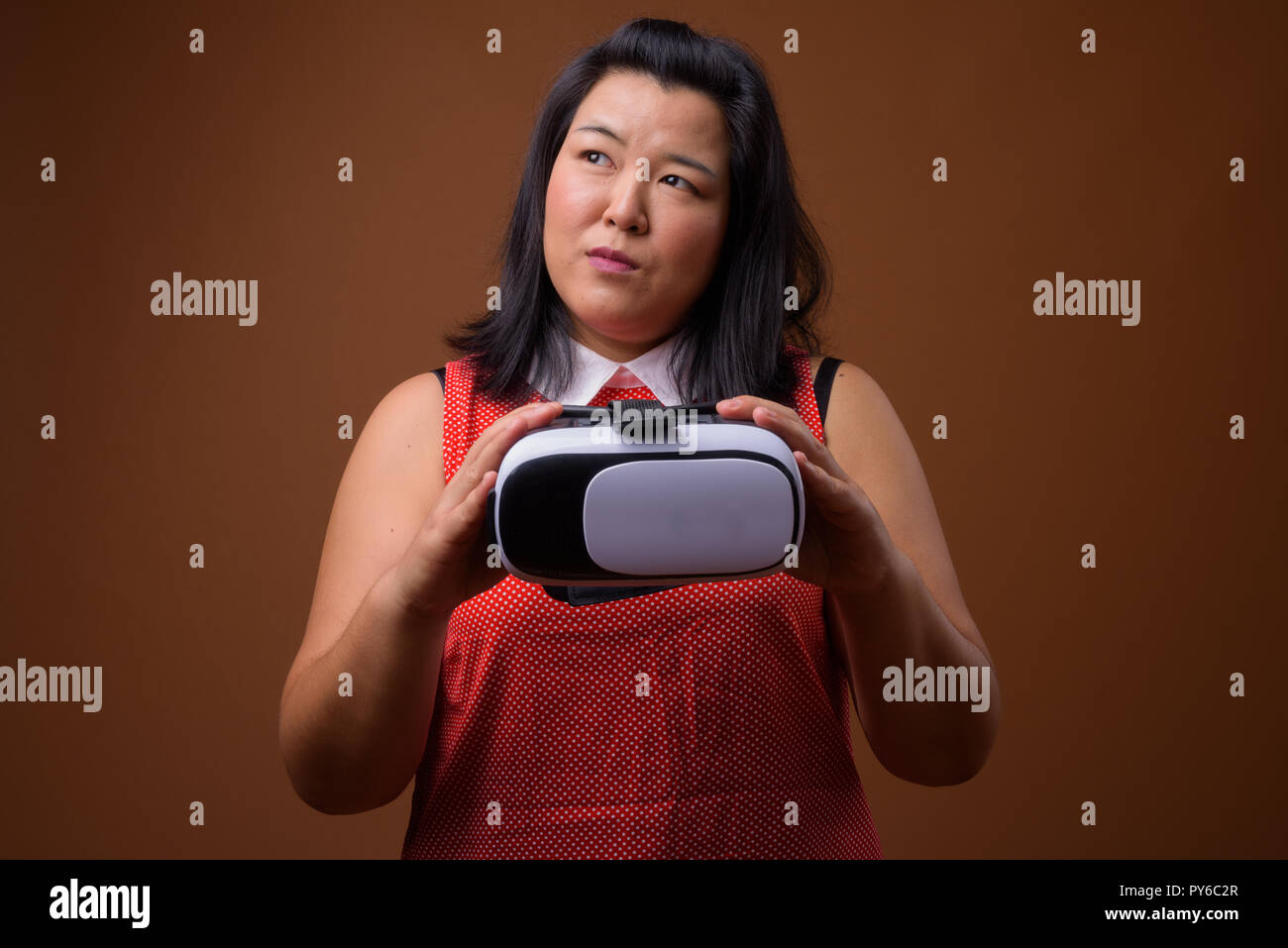 Schöne Übergewicht asiatische Frau mit Virtual Reality VR-Brille beim Denken Stockfoto