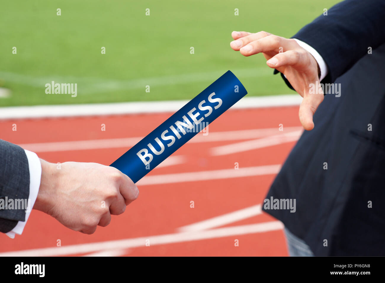 Close-up von zwei Geschäftsmann Hand vorbei an einem blauen Staffelstab im Stadion Stockfoto