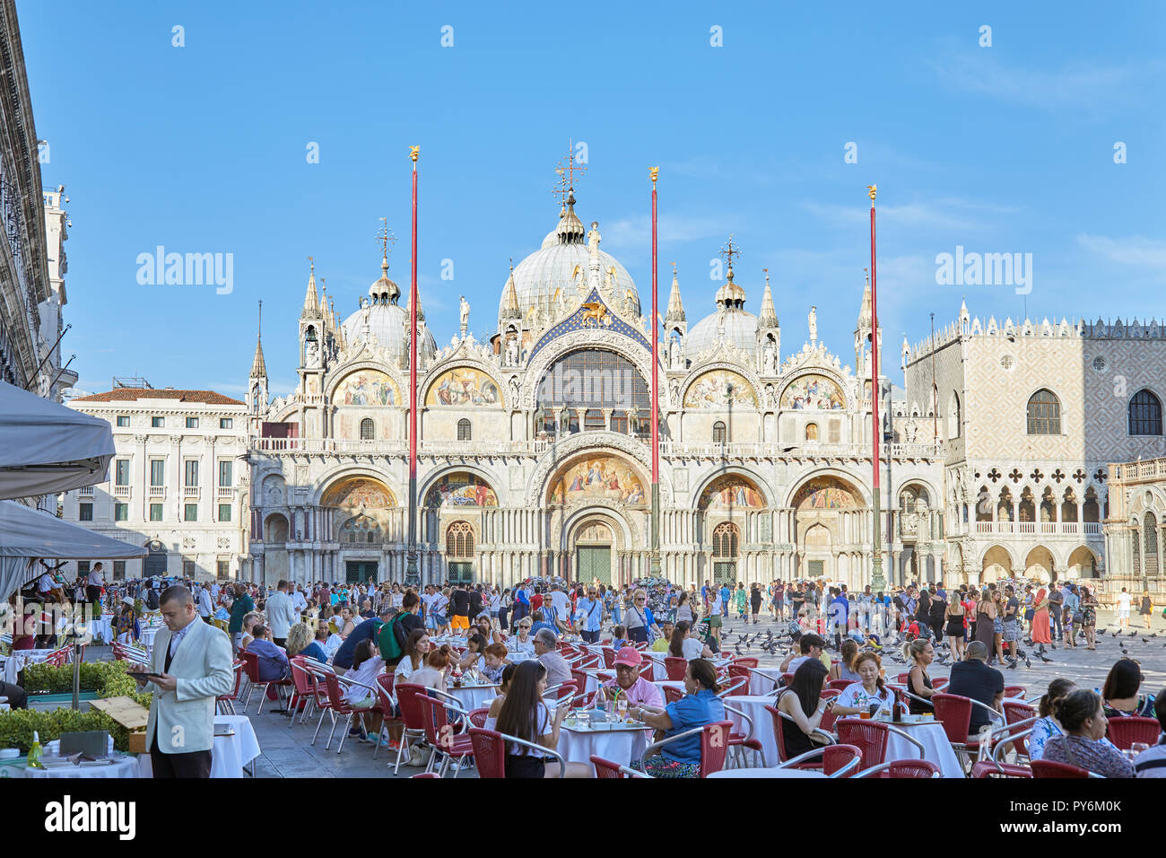 Venedig, Italien - 13 AUGUST 2017: Saint Mark Basilika Fassade und Platz mit Bürgersteig Tabelle mit Menschen und Touristen, blauer Himmel an einem sonnigen Sommertag im Stockfoto