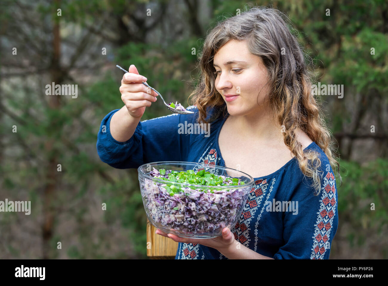 Junge Frau, Draußen, Draußen, holding Glas Schale hausgemachter rot, lila Kohl salat Teller mit grünen Zwiebeln, Frühlingszwiebeln mit Löffel in der Hand, Essen Stockfoto