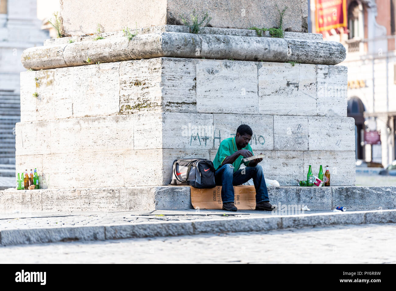 Rom, Italien, 4. September 2018: African Refugee Obdachlosen im City Park Essen von Obelisco an der Piazza Esquilino Platz sitzen Stockfoto