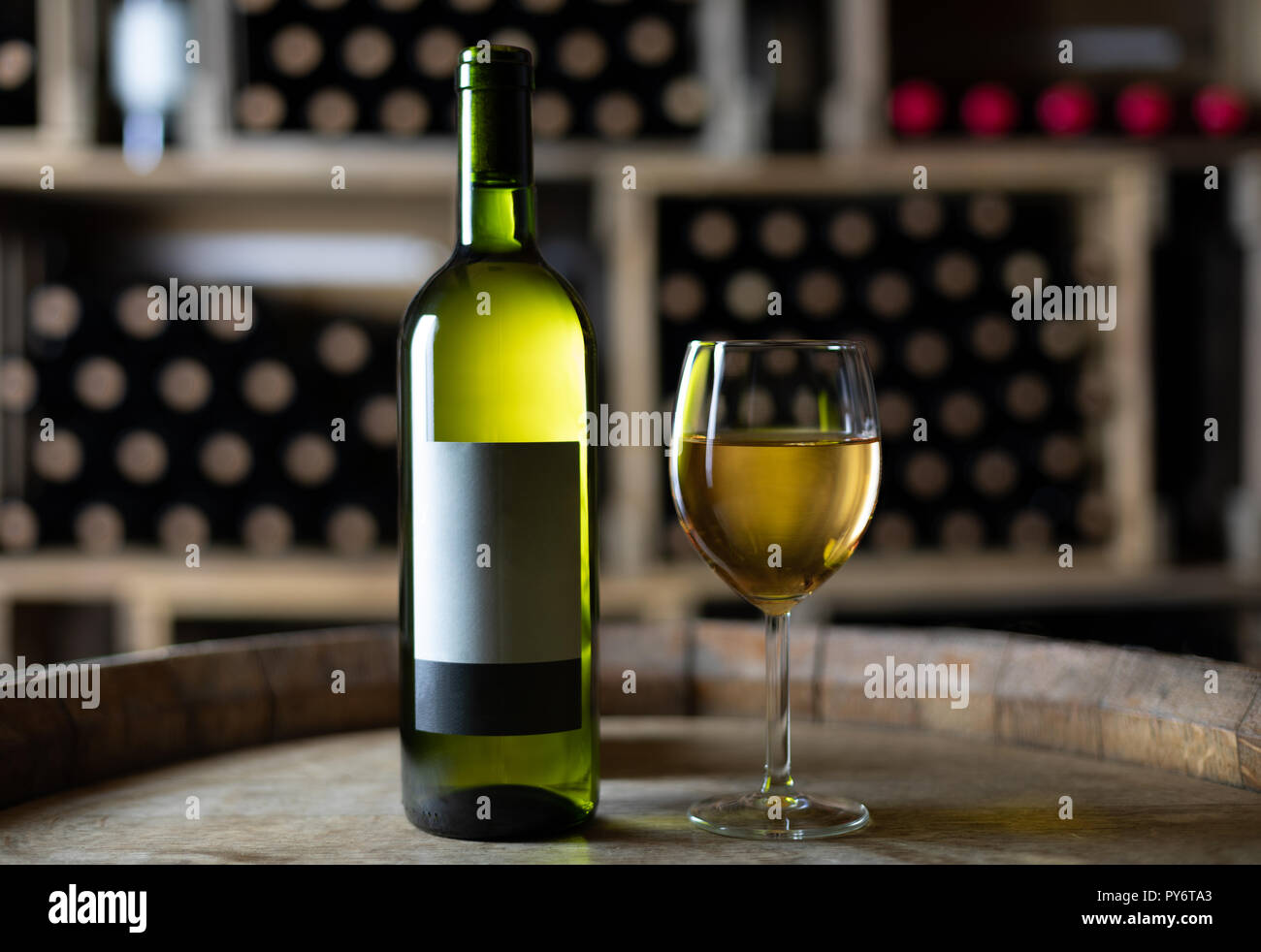 Weiße Flasche Wein mit einem gefüllten Weinglas auf einem Fass in einem  Keller, Schweiz Stockfotografie - Alamy