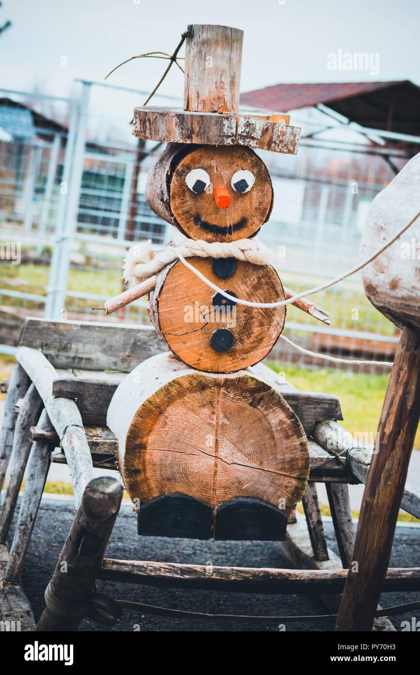 Einen schönen Schneemann aus Holz sitzt im Schlitten ist ein neues Jahr. Schlitten werden durch ein Reh geerntet. Sie bringen Weihnachten zu uns. Stockfoto