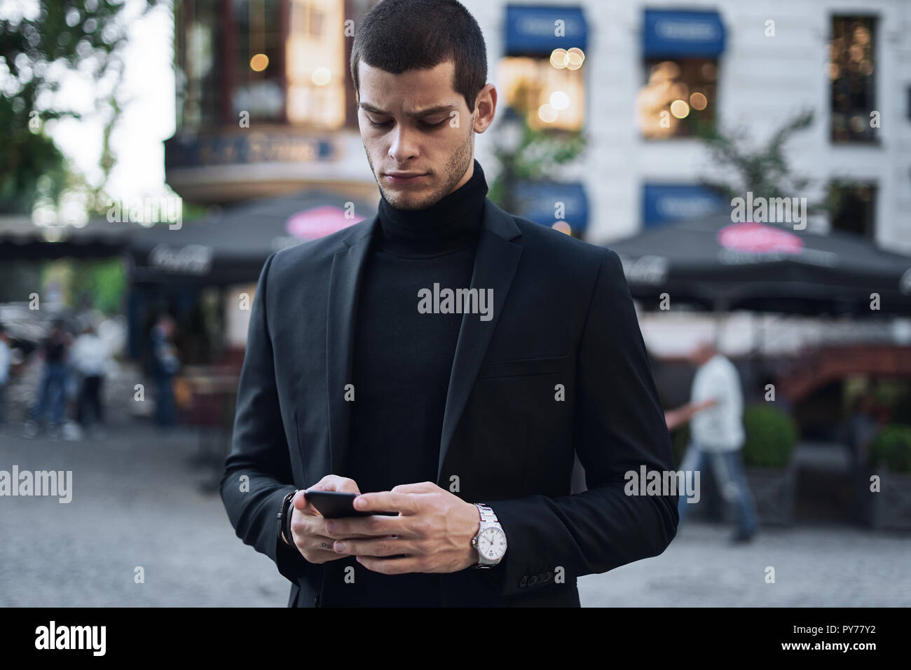 Geschäftsmann texting. Ernsthafte junge Geschäftsmann mit Mobiltelefon und es im Freien Stockfoto