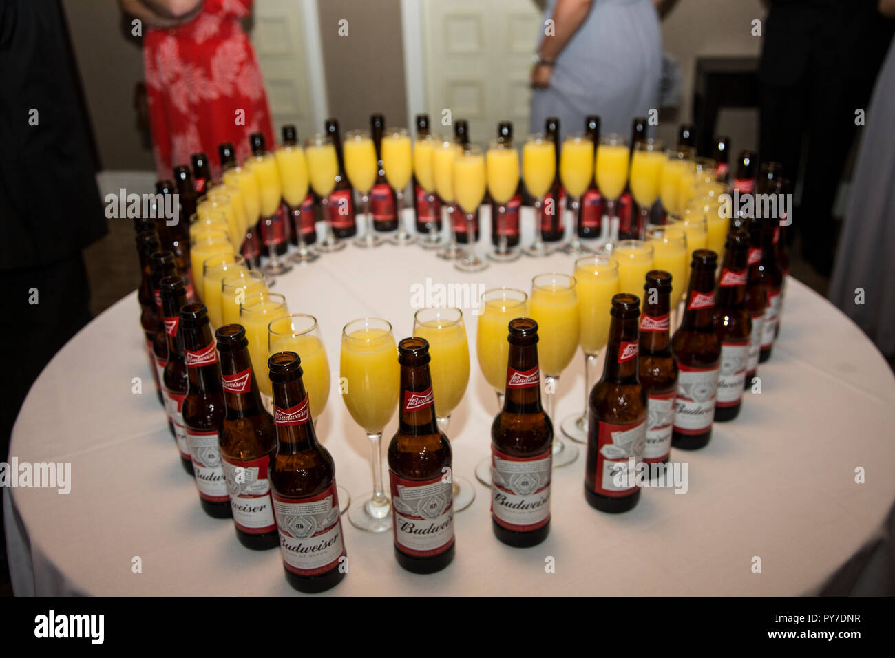 Flaschen Bier und Gläsern Orangensaft in der Form eines Herzens auf eine weiße Tischdecke auf einem runden Tisch Stockfoto