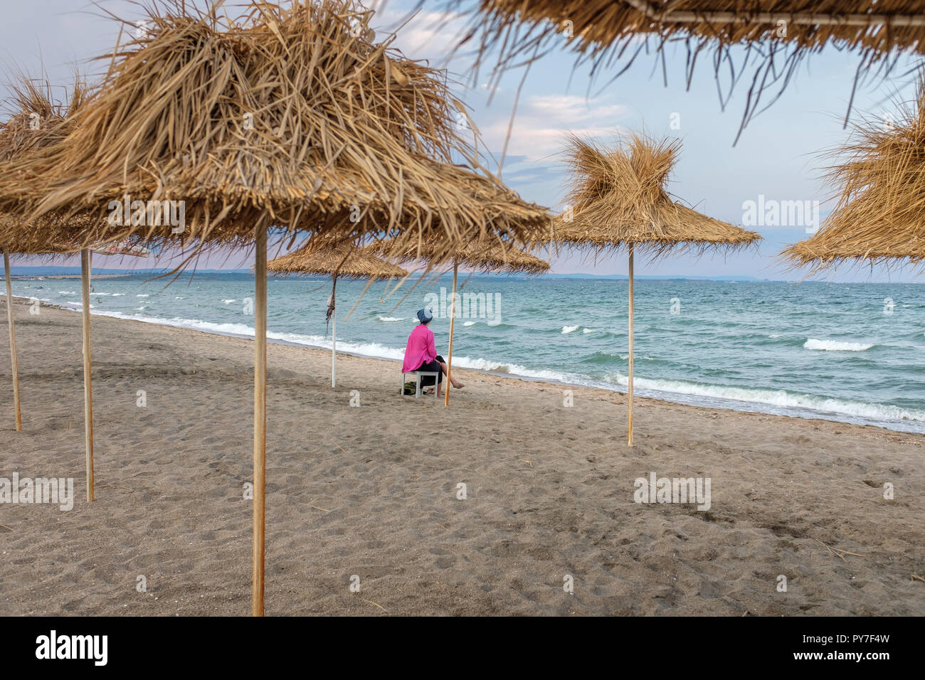 Frau Nachsinnen über den menschenleeren Strand am späten Nachmittag Stockfoto