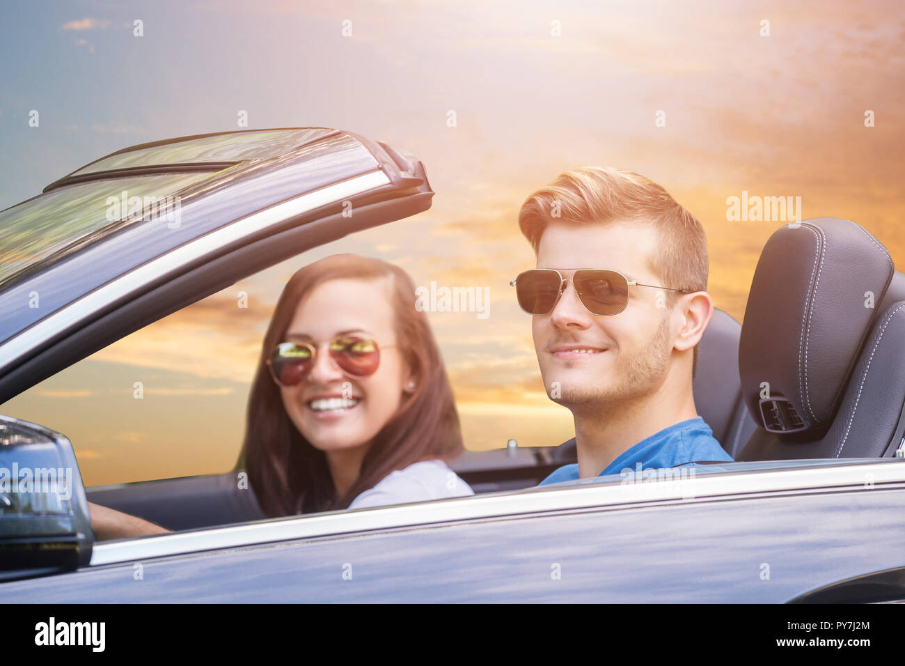 Junges Paar mit Sonnenbrille genießen Fahrt in einem Auto Stockfoto