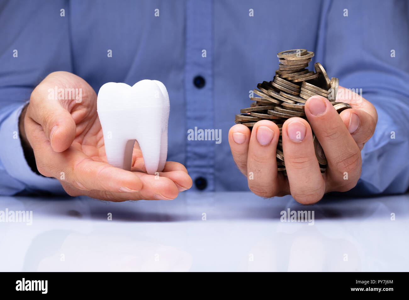 Close-up In eines Mannes Hand mit weißen Zähnen und goldenen Münzen über Schreibtisch Stockfoto