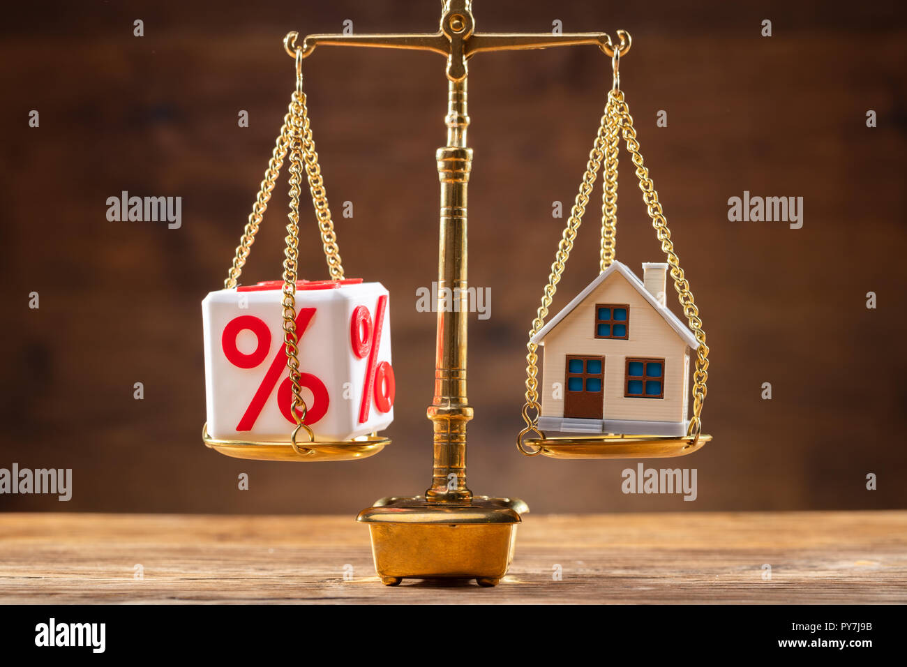 Golden Gerechtigkeit, welche Balance zwischen Prozentzeichen Block und Haus Modell auf hölzernen Schreibtisch Stockfoto