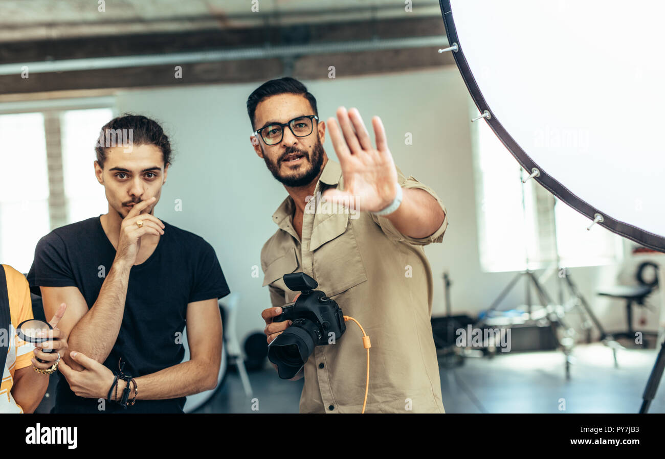 Fotografen arbeiten mit seinen Assistenten tun ein Fotoshooting im Studio. Fotograf mit seinem Team beim Fototermin mit Anpassungen. Stockfoto