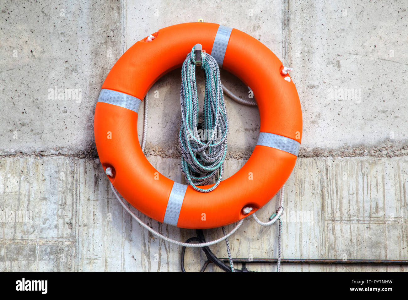 Rettung auf dem Wasser. Rettungsring auf dem Pier an der Wand Stockfoto